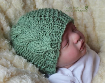Könnte beinhalten: Eine grüne gestrickte Baby-Mütze mit einem Zopfmuster. Die Mütze sitzt auf dem Kopf eines schlafenden Babys.