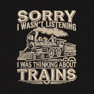 May include: Black square with embroidered text and a train illustration. The text reads "SORRY I WASN'T LISTENING I WAS THINKING ABOUT TRAINS" in a cream-colored, vintage-style font. The train is also cream-colored.