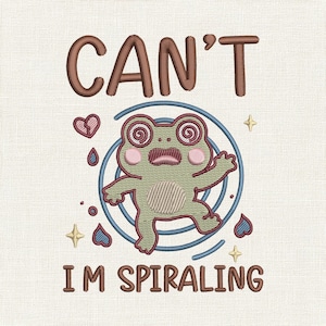 May include: Embroidered design featuring a cartoon frog with spiraling eyes, surrounded by a blue circle and hearts. The text "CAN'T I'M SPIRALING" is above and below the frog in brown thread. The design is on a cream-colored fabric.