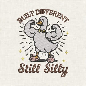 May include: Embroidered design of a strong goose flexing its arms, wearing a bow tie and bunny slippers. The text above reads "BUILT DIFFERENT", and below, "Still Silly". The design includes star accents and radiating lines.