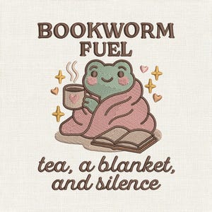 Op de afbeelding: Een borduurontwerp met een lichtgroene kikker gewikkeld in een roze deken, een mok met een hartje vasthoudend, naast een open boek. De tekst luidt BOOKWORM FUEL en tea, a blanket, and silence, omringd door kleine sterretjes en hartjes.