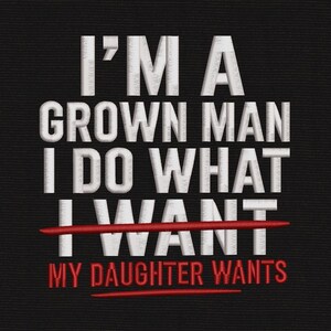 May include: An embroidered design on a black fabric background featuring the white text I'M A GROWN MAN I DO WHAT I WANT with a red horizontal line striking through the word WANT and the red text MY DAUGHTER WANTS positioned below the line.