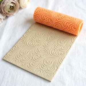 Könnte beinhalten: Eine weiße Keramik-Tasse mit schwarzem Henkel und dem Text "But First, Coffee" in fetter, schwarzer Schrift. Die Tasse steht vor einem verschwommenen Hintergrund, der eine gemütliche Umgebung suggeriert.