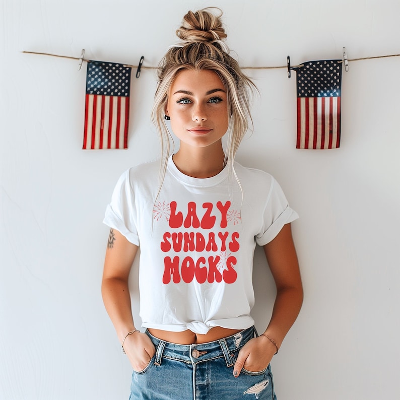 May include: White t-shirt with red text that says "Lazy Sundays Mocks" with a firework graphic on either side of the text.