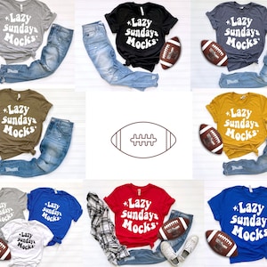 K&ouml;nnte beinhalten: Eine Sammlung von T-Shirts in verschiedenen Farben, jeweils kombiniert mit zerrissenen Jeans und einem Football. Die Shirts zeigen den Text "Lazy Sundays Mocks" in einer Retro-Schriftart. Farben sind Grau, Schwarz, Blau, Rot und Gold.