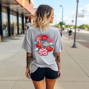 May include: A gray t-shirt with a graphic design of a disco ball, lips, hearts, and stars. The text "Good Vibes" is written in a retro font.