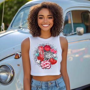 May include: White crop top with a colorful graphic design featuring a red can, a disco ball, red lips, and the text "Good Vibes".
