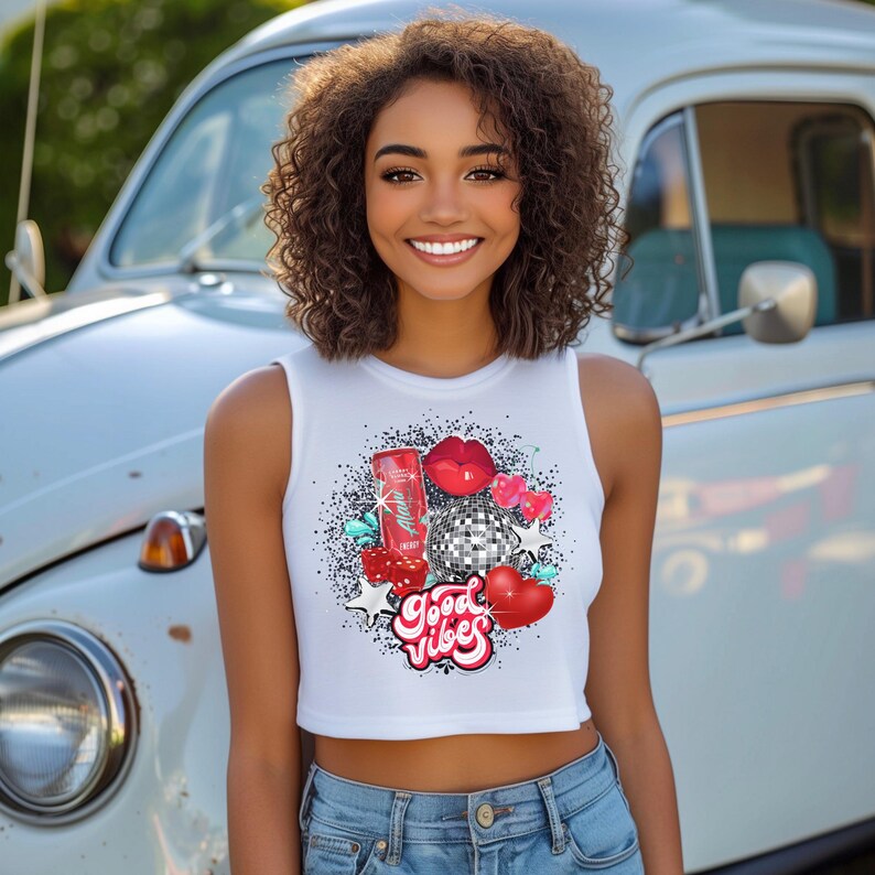 May include: White crop top with a colorful graphic design featuring a red can, a disco ball, red lips, and the text "Good Vibes".