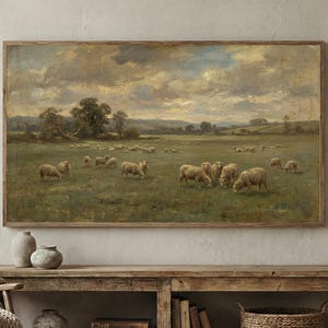 Può includere: Dipinto di paesaggio incorniciato che raffigura un gregge di pecore al pascolo in un campo verde sotto un cielo nuvoloso. L'opera d'arte ha un'estetica vintage, con una cornice in legno e una tavolozza di colori tenui.