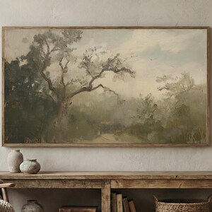 May include: A framed landscape painting with a muted color palette of greens, browns, and creams. The artwork depicts a large tree with sprawling branches, set against a soft, cloudy sky. The painting is displayed above a wooden console.