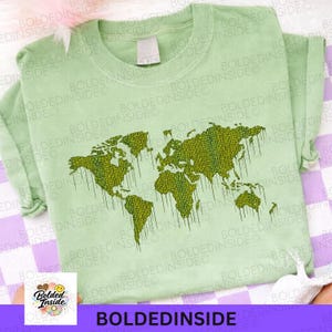 K&ouml;nnte beinhalten: Hellgr&uuml;nes T-Shirt mit einem Weltkarten-Design in Gr&uuml;nt&ouml;nen. Die Karte hat eine pixelige Textur mit Tropfeffekten. Der Text "BOLDEDINSIDE" ist am unteren Rand des Shirts aufgedruckt.