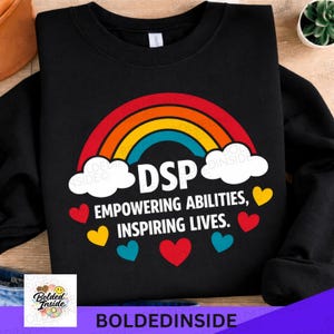 May include: Black sweatshirt featuring a rainbow design and the text "DSP Empowering Abilities, Inspiring Lives." The design includes white clouds, colourful hearts, and a rainbow arching over the text.