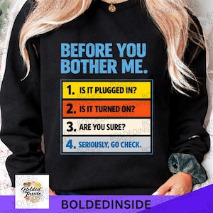 Puede incluir: Sudadera negra con el texto "BEFORE YOU BOTHER ME." Debajo, cuatro pasos numerados para la solución de problemas: "1. IS IT PLUGGED IN?", "2. IS IT TURNED ON?", "3. ARE YOU SURE?" y "4. SERIOUSLY, GO CHECK."