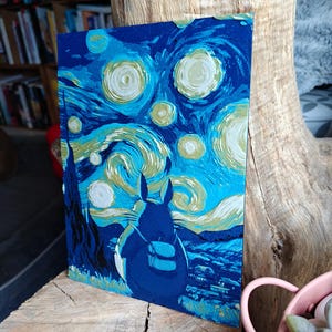 Puede incluir: Una impresión artística rectangular que representa una fusión de "La noche estrellada" de Van Gogh y un personaje Totoro azul. La obra de arte utiliza tonos de azul, con pinceladas arremolinadas y estrellas amarillas. La figura de Totoro está en primer plano.