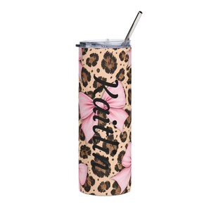 May include: A stainless steel tumbler with a leopard print design and pink bows. The name "Kaitlin" is printed vertically in black script. The tumbler includes a silver straw and a lid.
