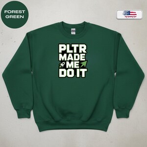 May include: Forest green sweatshirt with the text "PLTR MADE ME DO IT" in white block letters with a black outline. A rocket ship graphic is included. The sweatshirt has a crew neck and long sleeves.