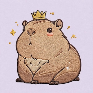 Op de afbeelding: Een geborduurde patch met een ronde, bruine capibara die een kleine gouden kroon draagt. De capibara heeft donkere ogen, roze blosjes op de wangen en is omringd door kleine, geborduurde gouden sterretjes en stippen op een lichtpaarse achtergrond.