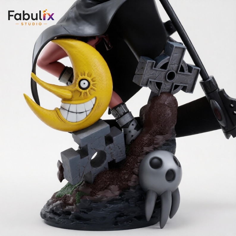 May include: A collectible figure featuring a yellow crescent moon with a wide, toothy grin and a single eye. The base includes a grey stone-like cross, a dark textured mound, and a small grey creature with three downward-pointing appendages.