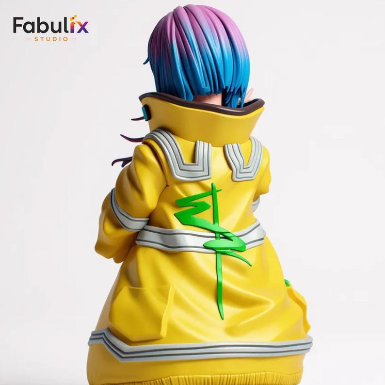 May include: A figurine of a character with blue and purple hair, wearing a bright yellow coat with green and silver accents. The coat has a high collar and a stylized green design on the back. The Fabulix Studio logo is in the top left corner.