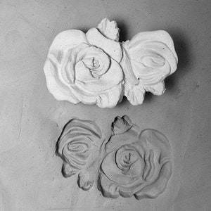 May include: Two white ceramic molds of roses, one with two roses and the other with two roses.