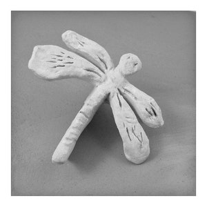 May include: A white ceramic dragonfly sculpture with detailed wings and a textured body.