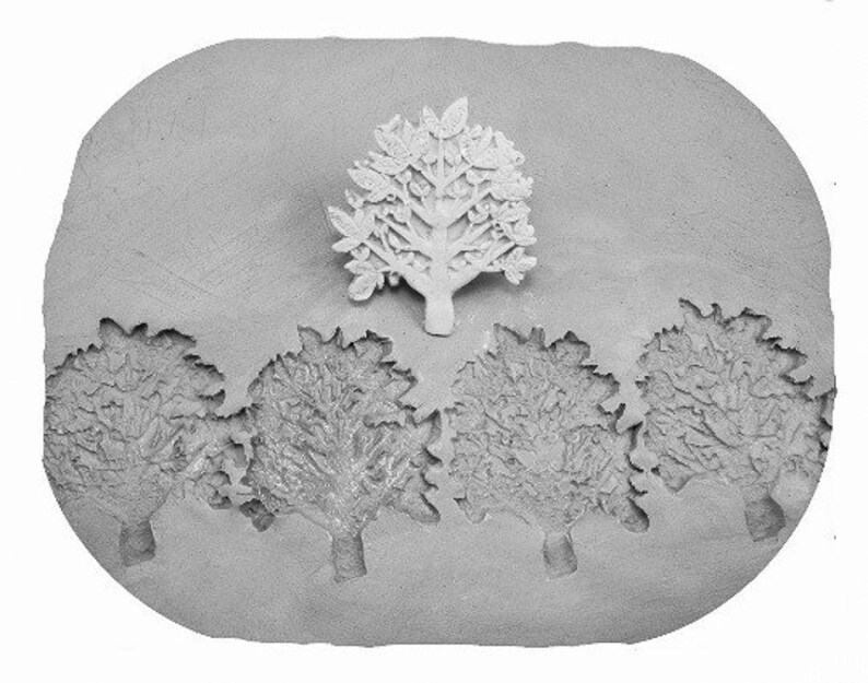 May include: A grey clay mould with five tree designs. The centre tree is raised and the four surrounding trees are indented.
