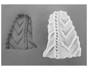 May include: Two ceramic pieces with a chevron pattern. One piece is a mold with a raised chevron pattern, and the other piece is a flat piece with an indented chevron pattern.