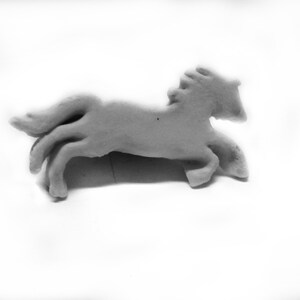 May include: A white ceramic horse figurine in a running pose. The horse has a detailed mane and tail.