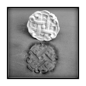 Może przedstawiać: Biała ceramiczna forma z wypukłym, skomplikowanym wzorem celtyckiego węzła. Forma jest wciśnięta w szarą powierzchnię, tworząc odcisk wzoru.