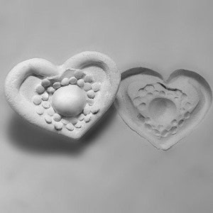 May include: Two white heart-shaped molds with a raised, textured design in the center of each heart.