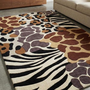 May include: A rectangular rug with a striking animal print design. The rug incorporates zebra stripes, leopard spots, and giraffe patterns in black, brown, and beige. The rug is placed on a concrete floor.