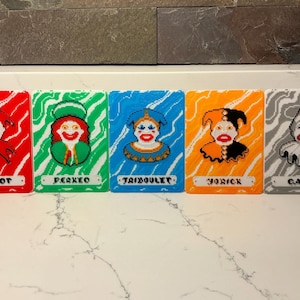 May include: Five colorful, pixelated portraits of jesters on rectangular cards. Each card features a different jester with a unique color scheme and name: Chicot, Perxeo, Taiboulet, Yorick, and Canio. The backgrounds are also color-coded.