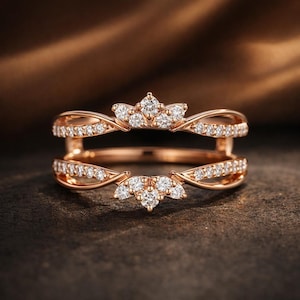 May include: Rose gold ring guard with a crown design, encrusted with small, sparkling diamonds. The ring features two bands that curve around each other, creating a unique and elegant look. The diamonds are set in a delicate pattern, adding to the ring's overall sparkle.