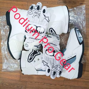 May include: White motorcycle boots and gloves. The boots and gloves are white with black and gray accents. The gloves have a unique design on the fingers. The text "Podium Pro Gear" is visible.