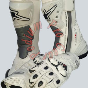 Puede incluir: Botas y guantes de moto blancos y negros. Las botas tienen un diseño alto con detalles en negro y gris, y los guantes tienen acolchado negro. Las botas y los guantes tienen el logotipo de la marca.