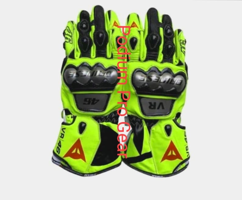 May include: A pair of neon yellow and black motorcycle gloves featuring hard knuckle protectors, the text VR 46, and a red triangular logo. The gloves display the Dainese brand name on the knuckle guards and include additional protective padding.