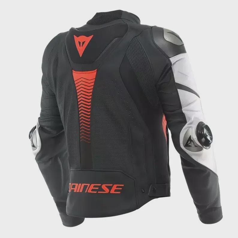 Peut inclure: Veste de moto noire et blanche avec des d&eacute;tails rouges. La veste pr&eacute;sente un col montant, des &eacute;paules rembourr&eacute;es et le mot "AINESE" en rouge. Le dos comporte un motif en chevrons rouges et un logo rouge. Les manches ont des panneaux blancs et noirs.