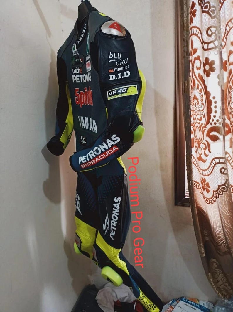 May include: A black, blue, and neon yellow motorcycle racing suit featuring various sponsor logos including Petronas, Yamaha, and VR46. The suit has protective shoulder caps, long sleeves, and full-length legs with integrated knee sliders.