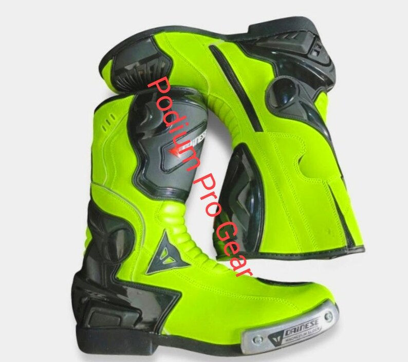 May include: A pair of neon yellow and black motorcycle boots featuring the Dainese logo on the side and a metallic toe slider with the text Podium Pro Gear overlaid on the image. The boots have a high-cut design with reinforced black panels.