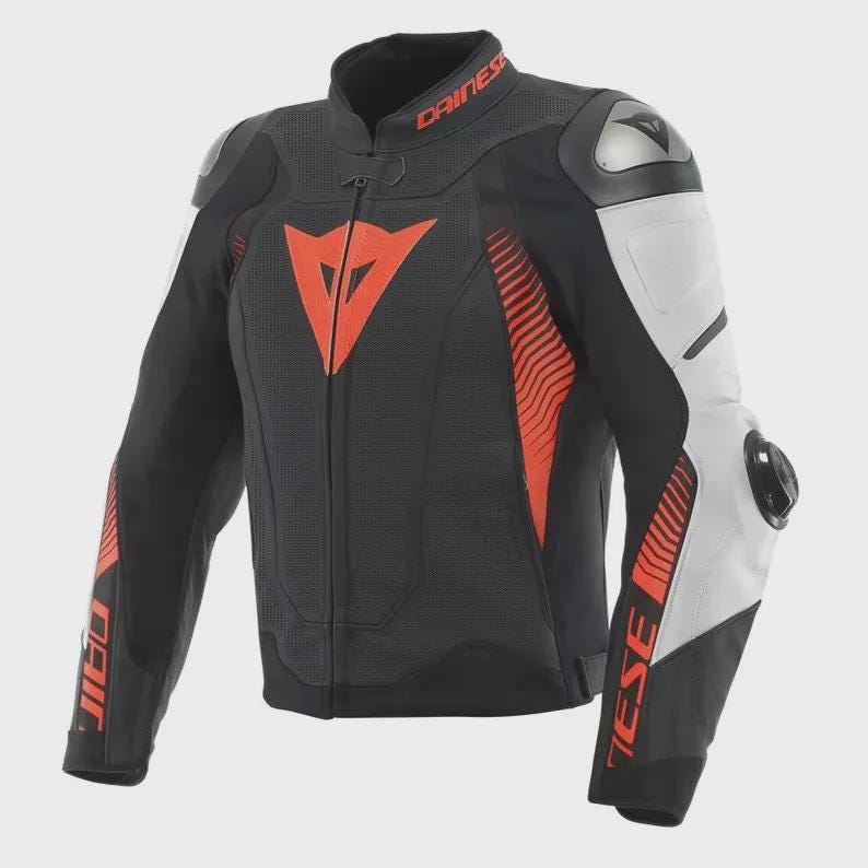 Peut inclure: Veste de moto noire et blanche avec des d&eacute;tails rouges. La veste a un col montant, une fermeture &eacute;clair et des protections aux &eacute;paules. La marque "DAINESE" est visible sur le col. La veste pr&eacute;sente un design sportif.