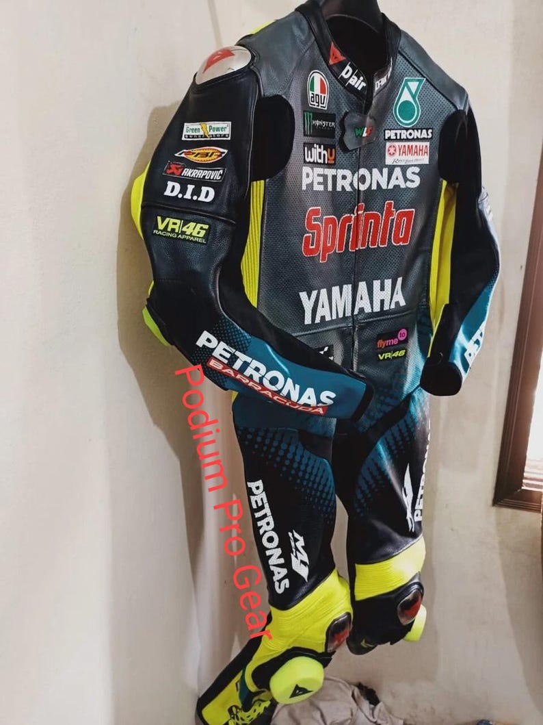 May include: A black, teal, and neon yellow leather motorcycle racing suit featuring multiple sponsor logos including Petronas, Yamaha, Sprinta, and VR46. The suit has a full-length front zipper, protective padding at the shoulders and knees.