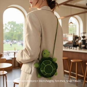 Puede incluir: Un bolso bandolera verde con forma de tortuga de ganchillo. El bolso mide 11cm (arriba) x 14cm (abajo) x 30cm (alto), 7cm de grosor, con una correa de 136cm. El bolso tiene un diseño de caparazón redondo y una correa larga verde.