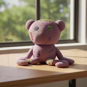May include: A lavender-coloured teddy bear with stitched details and patches. The bear, approximately 22 cm tall, has a stitched smile, a button eye, and patches on its head and limbs, giving it a unique, handcrafted appearance.