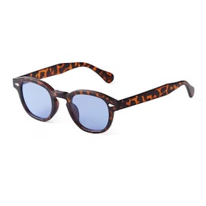 Peut inclure: Lunettes de soleil rondes avec un motif écaille de tortue et des verres bleus. Le design classique comprend un pont en trou de serrure. Les montures sont faites d'un matériau durable.