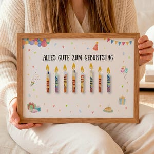 Könnte beinhalten: Ein rechteckiger Holzrahmen mit einem weißen Druck, der den deutschen Text ALLES GUTE ZUM GEBURTSTAG zeigt. Das Design umfasst acht brennende Kerzen, bunte Luftballons, Partyhüte und Geschenkboxen, die im Aquarellstil illustriert sind.
