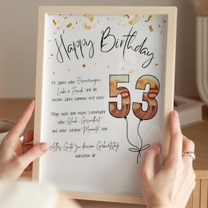 Könnte beinhalten: Ein gerahmter Geburtstagsdruck mit den Worten "Happy Birthday" in eleganter Schrift. Die Zahl "53" ist als Ballons gestaltet. Der Druck enthält zusätzlichen Text auf Deutsch, mit Konfetti-Akzenten, und wird von einer Person gehalten.