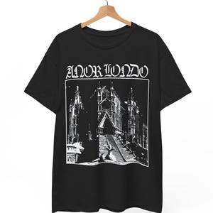 May include: Black t-shirt with a white graphic of a cathedral and the text "ANOR LONDO" in a gothic font. The design features detailed architectural elements and a staircase leading to the cathedral entrance. The shirt is hanging on a wooden hanger.