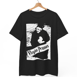 May include: Black t-shirt featuring a white graphic of a person holding an object, with the text "Virgin Prunes" in a banner below. The design is a bold, monochrome illustration.