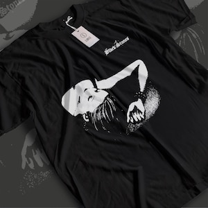 May include: Black t-shirt featuring a white graphic of a person's face and arm, with the text "Black Stones" in a gothic font. A tag indicates the size is Large.