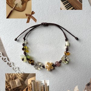 Puede incluir: Una delicada pulsera con un cordón marrón, adornada con cuentas florales claras, amarillas y rosas. El diseño de la pulsera incorpora una mezcla de texturas y colores, creando un accesorio encantador.